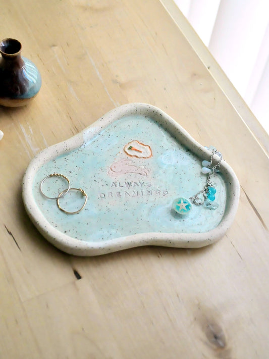 Light blue ceramic trinket dish with jewelry on a wooden surface
