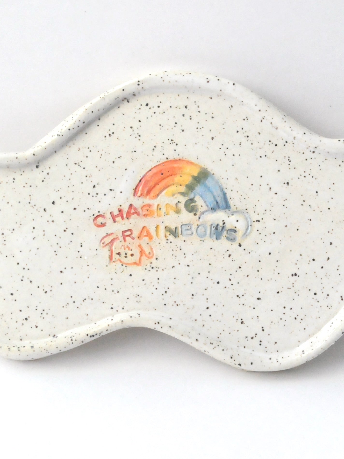 White specked trinket dish with a rainbow design on a white background