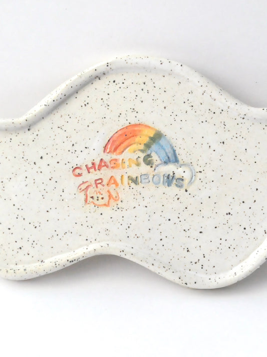 White specked trinket dish with a rainbow design on a white background
