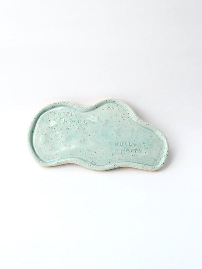 Blue ceramic dish with 'Partly Cloudy Fully Happy text on a white background
