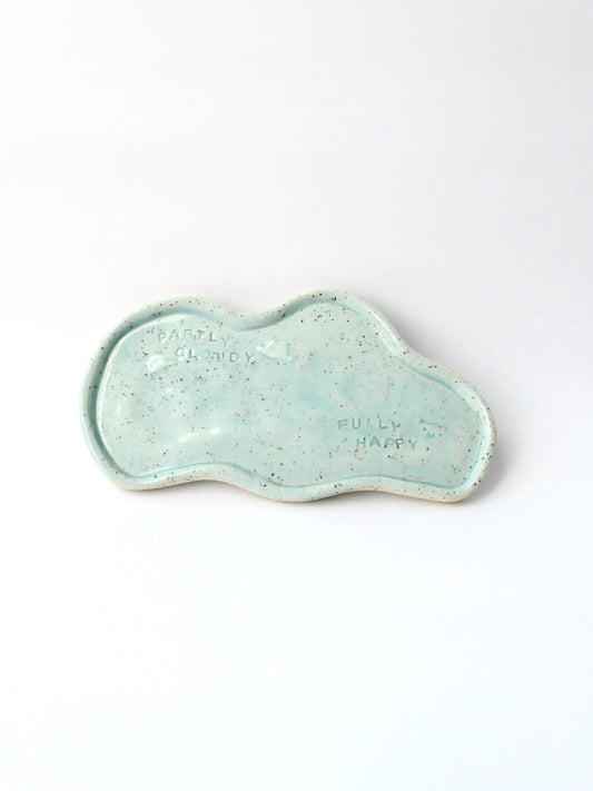 Blue ceramic dish with 'Partly Cloudy Fully Happy text on a white background