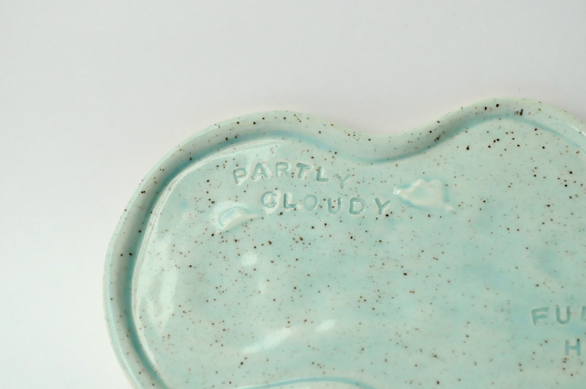 Blue ceramic dish with 'Partly Cloudy Fully Happy text on a white background