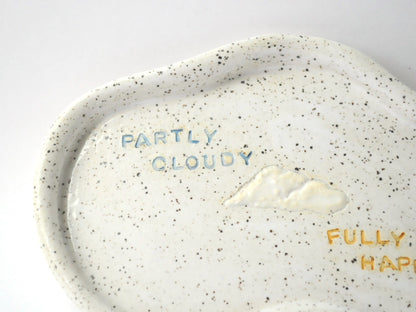 Speckled ceramic plate with cloud design and text on a white background
