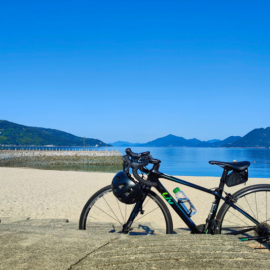 Bicycle with helmet and water bottle on a concrete surface with a scenic background of mountains and sea on the Shimanami Kaido, Japan.